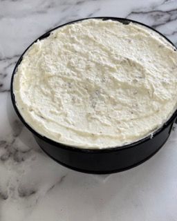 Una padella nera piena di glassa bianca è appoggiata su un tavolo.