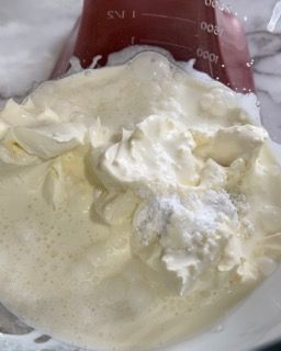 Primo piano di una ciotola di panna montata accanto a un misurino.