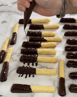 Una persona sta glassando un mucchio di biscotti con il cioccolato