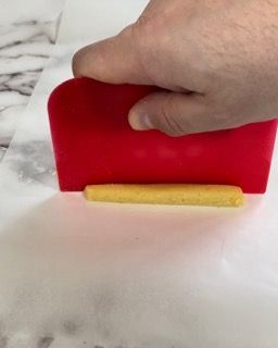 Una persona tiene in mano una spatola rossa su una superficie bianca.