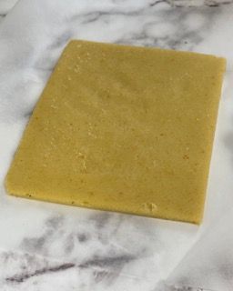 Un pezzo di pasta è appoggiato su un foglio di carta oleata su un tavolo.