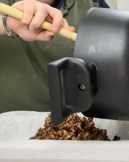 Una persona sta versando le noci in un contenitore con un bastoncino di legno