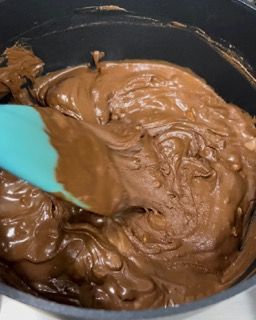 Una pentola di salsa al cioccolato con una spatola dentro.