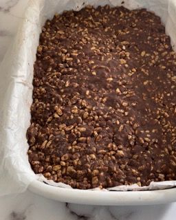 Una teglia bianca piena di cioccolato e noci su un tavolo.