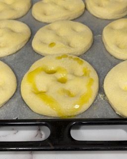 Un mucchio di ciambelle sono appoggiate su un vassoio con sopra dell'olio