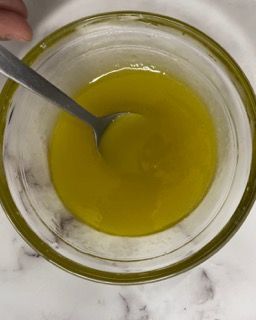 Una ciotola di liquido giallo con un cucchiaio dentro.