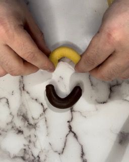 Una persona sta disegnando una faccina sorridente con il cioccolato su una superficie di marmo.