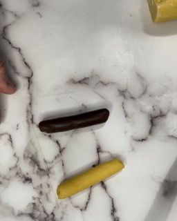 Una persona tiene in mano un pezzo di cioccolato su un bancone di marmo.