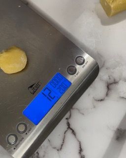 Una bilancia in acciaio inossidabile con uno schermo blu che mostra 12 grammi