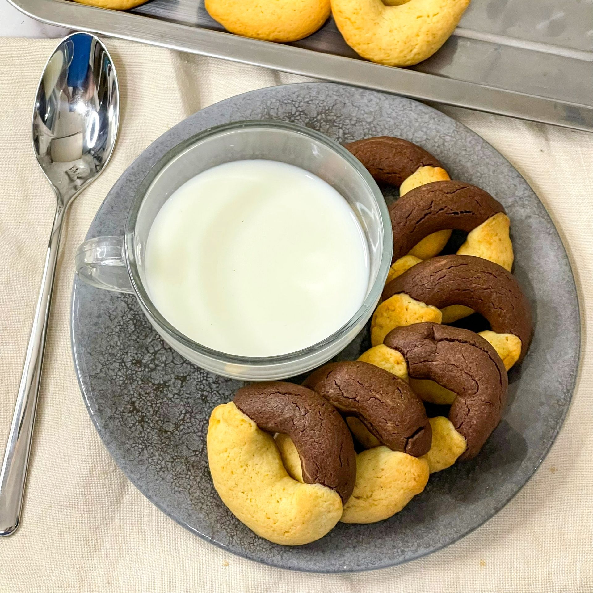 Un piatto di biscotti e una tazza di latte su un tavolo.