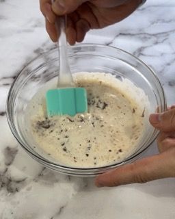 Una persona sta mescolando qualcosa in una ciotola con una spatola.