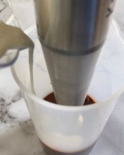 Una persona versa il latte in un misurino.