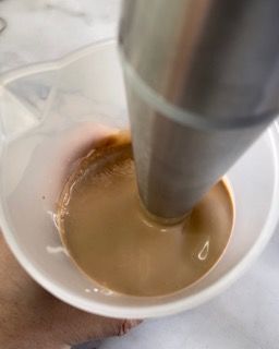 Una persona versa il caffè in una tazza graduata.