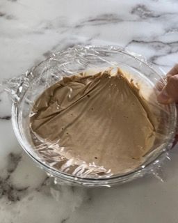 Una persona tiene in mano una ciotola di cibo avvolta nella pellicola trasparente.