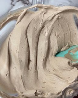 Primo piano di una ciotola di glassa al cioccolato con una spatola al suo interno.