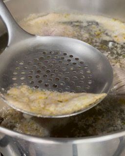 Si usa un mestolo per raccogliere il cibo da una pentola di zuppa.