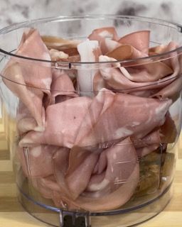 Una ciotola trasparente piena di carne affettata su un tavolo