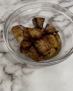 Una ciotola di vetro piena di carne e salsa su un tavolo.