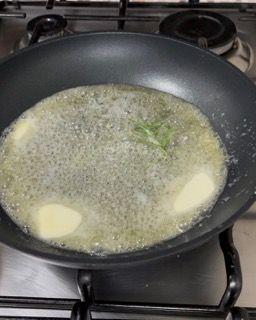 Una padella piena di burro ed erbe aromatiche su un fornello