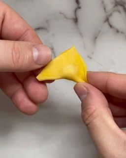 Una persona tiene in mano un pezzo di formaggio giallo.