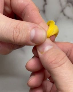 Una persona tiene un oggetto giallo tra le dita.