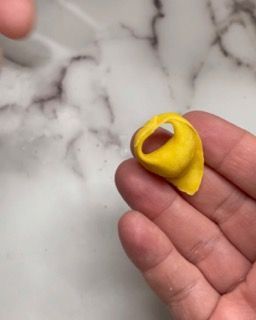 Una persona tiene in mano un piccolo oggetto giallo.