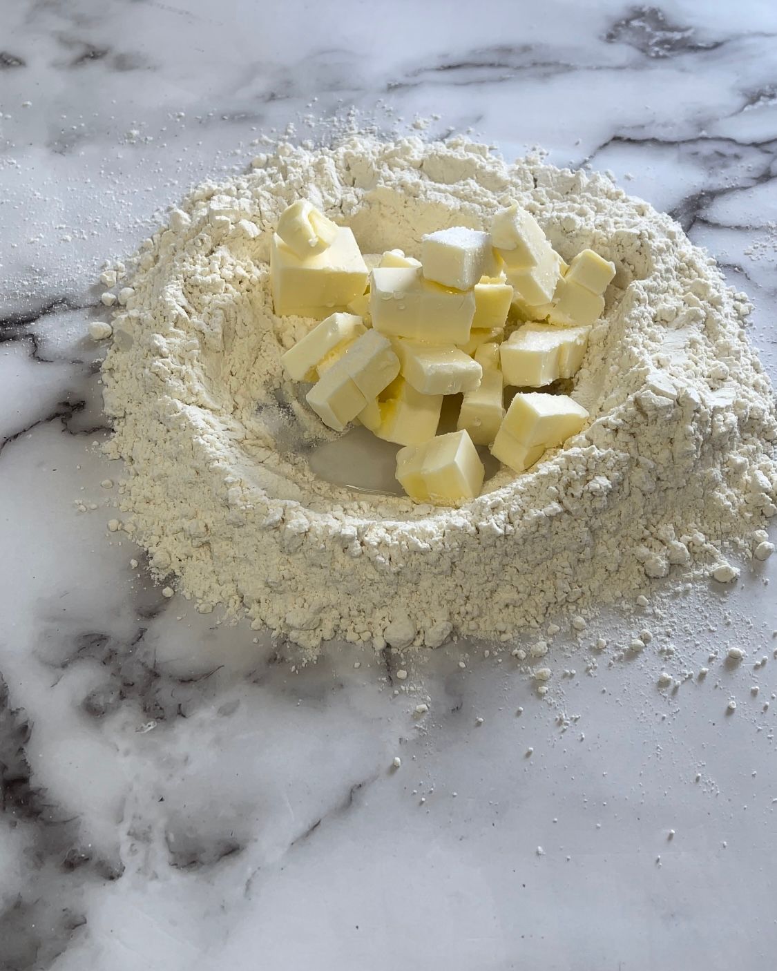 Un mucchio di farina e burro su una superficie di marmo.