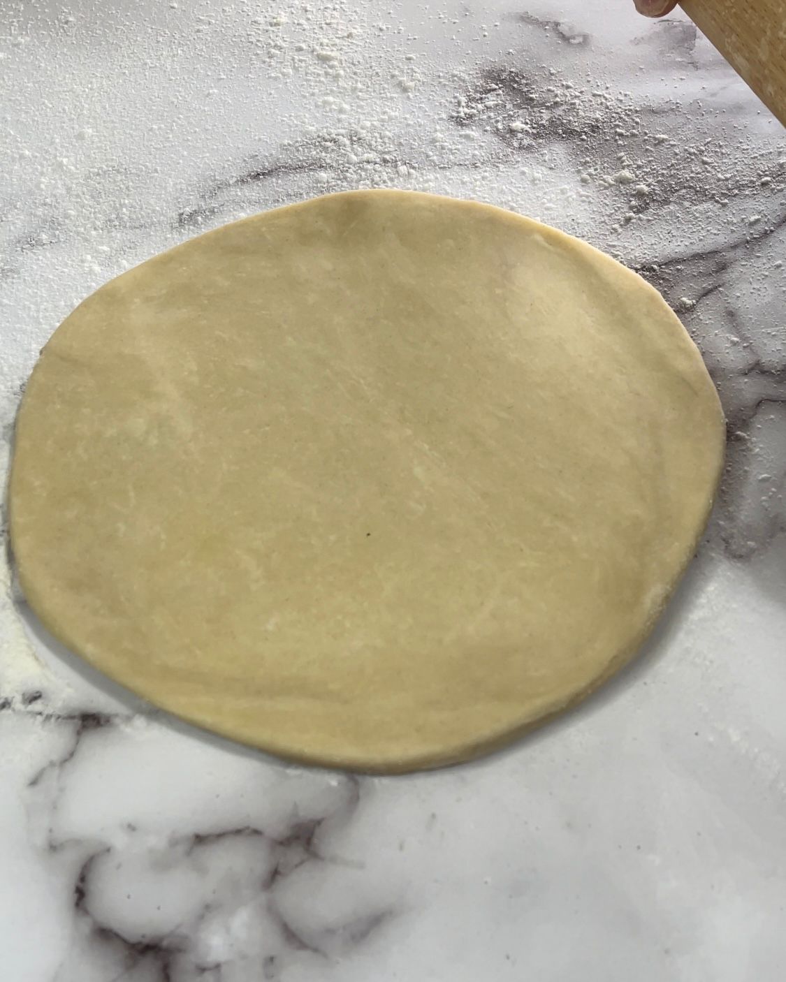 Un pezzo di pasta viene steso su una superficie di marmo.