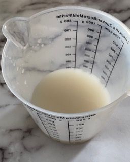 Un misurino riempito con un liquido bianco su cui è scritto