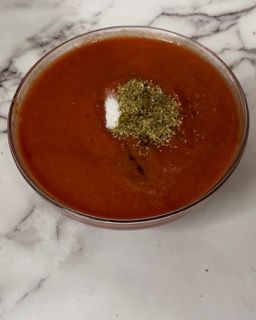 Una ciotola di zuppa di pomodoro con un rametto di prezzemolo sopra.