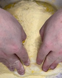Una persona impasta l'impasto con le mani in una ciotola.