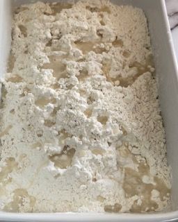 Una teglia bianca piena di farina e liquido.