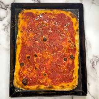 Una pizza con salsa di pomodoro e olive in padella