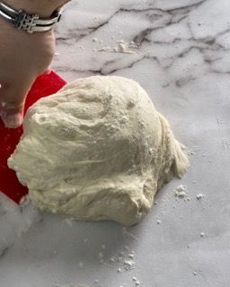 Una persona tiene in mano una spatola rossa sopra una pila di pasta.