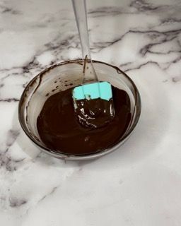 Una ciotola di salsa al cioccolato con una spatola dentro.