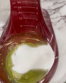 Un misurino rosso pieno di liquido e schiuma su un tavolo.