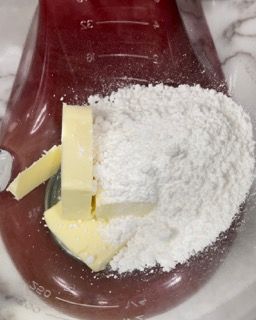 Un becher rosso pieno di zucchero a velo e burro