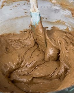 Una ciotola di glassa al cioccolato con una spatola dentro.