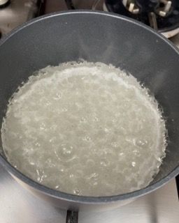 Una pentola piena di liquido cuoce sul fornello.