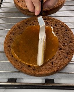Una persona sta spalmando del caramello su una torta al cioccolato