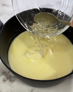 Una persona versa del liquido in una pentola con un cucchiaio.