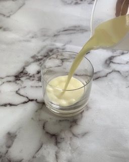 Una persona sta versando il latte in un bicchiere su un tavolo.