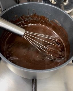 Una pentola di salsa al cioccolato con una frusta dentro