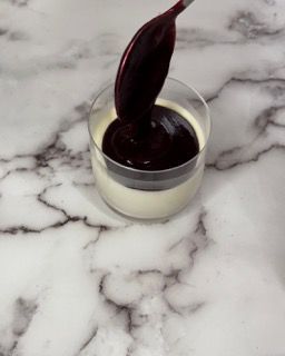 Un cucchiaio spunta da una tazza di salsa su un tavolo.