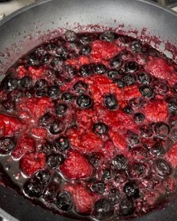 Una padella piena di bacche e salsa con un cucchiaio dentro