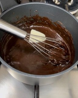 Una pentola di salsa al cioccolato con una frusta dentro