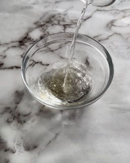 L'acqua viene versata in una ciotola di vetro su una superficie di marmo.