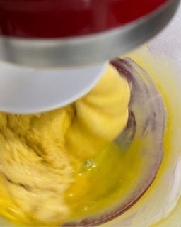 Un mixer sta mescolando un liquido giallo in una ciotola di vetro.