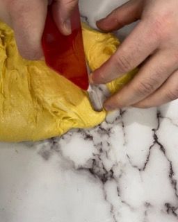 Una persona tiene in mano un oggetto giallo e rosso su una superficie di marmo.