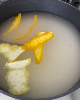 Una pentola con acqua e scorza di limone dentro.